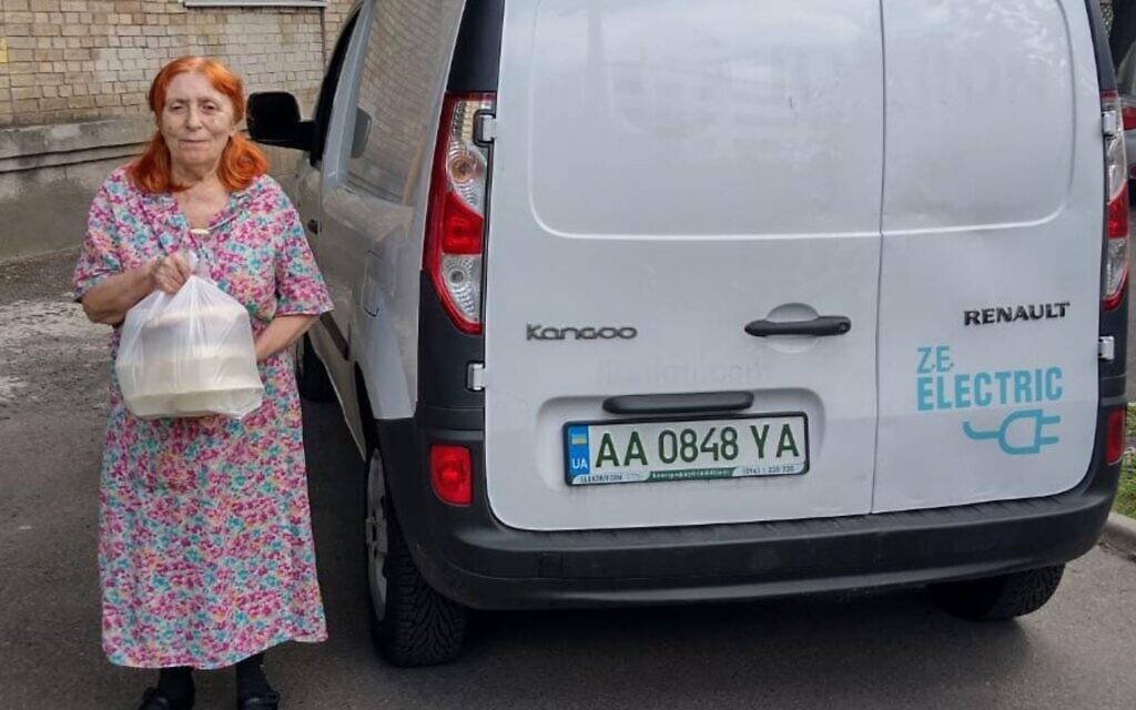 A woman takes out an aid package from an electric car owned by the Jewish Federations of Ukraine in Kyiv, Ukraine, August 1, 2022. (Courtesy of the Jewish Federations of Ukraine/ via JTA) A woman takes out an aid package from an electric car owned by the Jewish Federations of Ukraine in Kyiv, Ukraine, August 1, 2022. (Courtesy of the Jewish Federations of Ukraine/ via JTA)