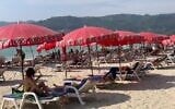Tourists lounge under umbrellas along Patong Beach in Phuket, Thailand, Friday, March 11, 2022. (AP Photo/Salinee Prab)