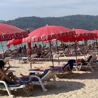 Tourists lounge under umbrellas along Patong Beach in Phuket, Thailand, Friday, March 11, 2022. (AP Photo/Salinee Prab)