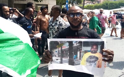 A man shows a picture of the victim Nigerian street vendor Alika Ogorchukwu, in Civitanova Marche, Italy, July 30, 2022. (AP/Chiara Gabrielli)
