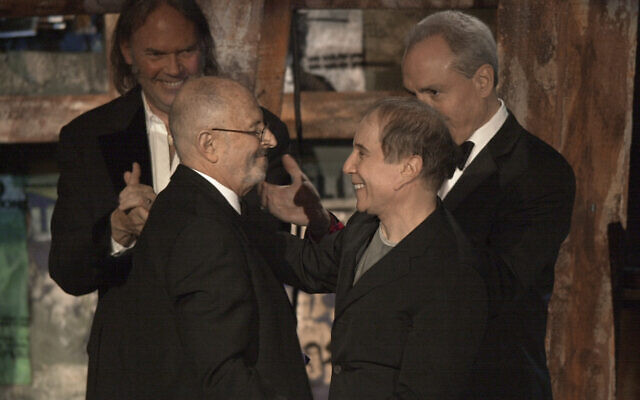 Record executive Mo Ostin, foreground left, is embraced by singer/songwriter Paul Simon, right, as singer/songwriter Neil Young, background left, and producer Lorne Michaels look on after Ostin was inducted into the Rock and Roll Hall of Fame in New York on March 10, 2003. (Gregory Bull/AP) Record executive Mo Ostin, foreground left, is embraced by singer/songwriter Paul Simon, right, as singer/songwriter Neil Young, background left, and producer Lorne Michaels look on after Ostin was inducted into the Rock and Roll Hall of Fame in New York on March 10, 2003. (Gregory Bull/AP)