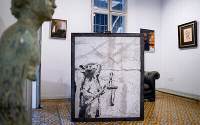 A painting by the secretive British graffiti artist Banksy that was mysteriously transferred from the West Bank is revealed in Urban Gallery in Tel Aviv, Israel, Thursday, Aug. 4, 2022. . (Oded Balilty/AP)