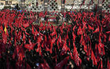 Mourners wave red flags as they gather around flag-draped coffins of five members of the paramilitary Revolutionary Guard killed in Syria, whose remains were recently recovered, during their funeral ceremony in Tehran, Iran, August 4, 2022. (AP/Vahid Salemi)