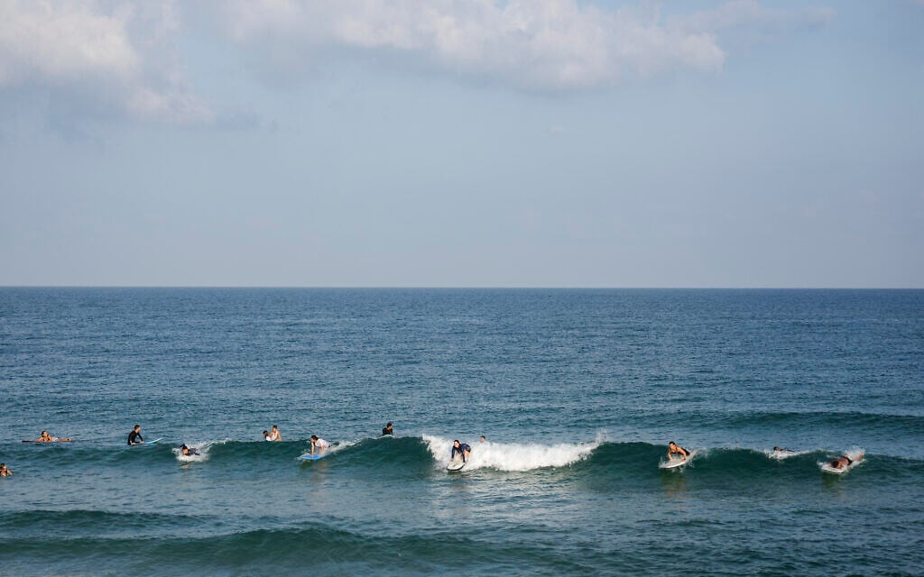 Surfers enjoy the early morning in the Mediterranean Sea off the southern coastal city of Ashkelon on August 8, 2022, following a ceasefire between the Israel and Gaza-based Palestinian Islamic Jihad. (AP Photo/Ariel Schalit)