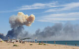 Rising smoke can be seen from the beach at Saky after explosions were heard from the direction of a Russian military airbase near Novofedorivka, Crimea, August 9, 2022. (UGC via AP)