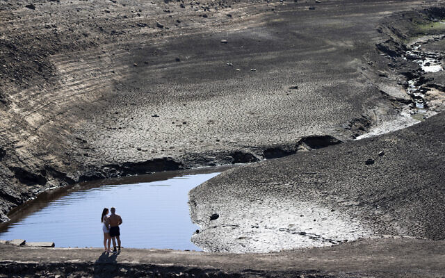 Members of the public stand on what was an ancient packhorse bridge exposed by low water levels at Baitings Reservoir in Yorkshire as record high temperatures are seen in the UK, Ripponden, England, Friday, Aug. 12, 2022. Low water levels at the reservoir have revealed the remains of the ancient road flooded to build the reservoir in the 1950s. (AP Photo/Jon Super) Members of the public stand on what was an ancient packhorse bridge exposed by low water levels at Baitings Reservoir in Yorkshire as record high temperatures are seen in the UK, Ripponden, England, Friday, Aug. 12, 2022. Low water levels at the reservoir have revealed the remains of the ancient road flooded to build the reservoir in the 1950s. (AP Photo/Jon Super)