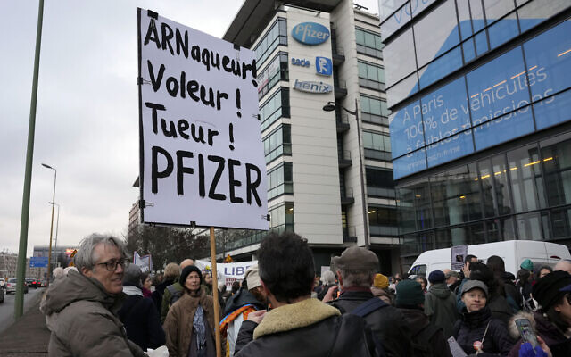Illustrative: A demonstrator holds a placard reading 'Scammer, thief, killer, Pfizer' during a protest against the vaccine pass and vaccinations to protect against COVID-19 in front of the Pfizer headquarters, in Paris, on January 29, 2022. (AP Photo/Thibault Camus, File) Illustrative: A demonstrator holds a placard reading 'Scammer, thief, killer, Pfizer' during a protest against the vaccine pass and vaccinations to protect against COVID-19 in front of the Pfizer headquarters, in Paris, on January 29, 2022. (AP Photo/Thibault Camus, File)
