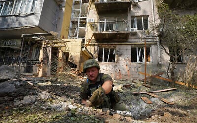 A Ukrainian serviceman collects fragments in the crater to determine the type of ammunition after a Russian attack that damaged some buildings in Kharkiv, Ukraine, August 30, 2022. (AP Photo/Andrii Marienko)