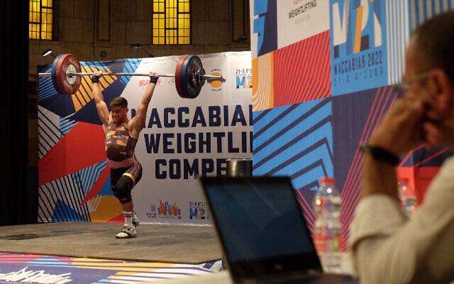 South African Keegan David Cohen lifts a barbell during the clean-and-jerk segment of the Maccabiah's weightlifting competition in Jerusalem on July 19, 2022. (Judah Ari Gross/Times of Israel)