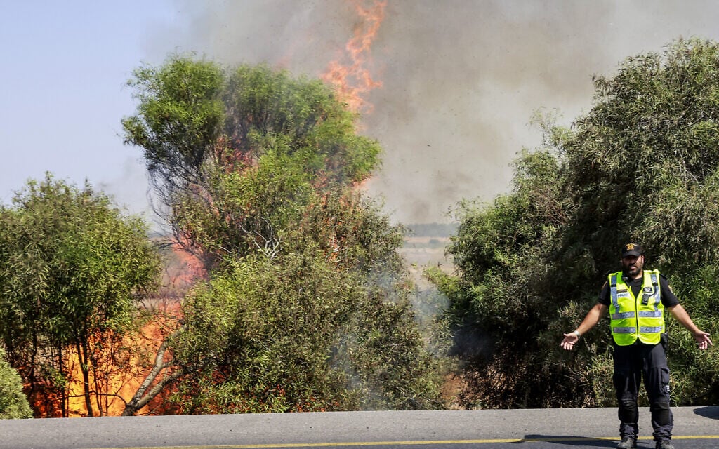 Israeli police officers at the scene of a fire caused after a rocket launched from the Gaza Strip hit a field near Sderot, August 7, 2022. (Yossi Zamir/Flash90)