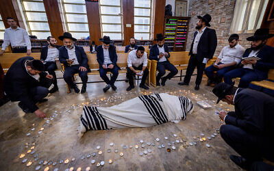 Jewish men pray near the body Rabbi Shalom Cohen, the spiritual leader of the ultra-Orthodox Shas party, at a synagogue in Jerusalem on August 22, 2022. (Yonatan Sindel/Flash90)