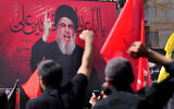 File: Hezbollah terror leader Hassan Nasrallah speaks via a video link, as his supporters raise their hands, during the Shiite holy day of Ashoura, in a southern suburb of Beirut, Lebanon, August 9, 2022. (AP Photo/Hussein Malla)