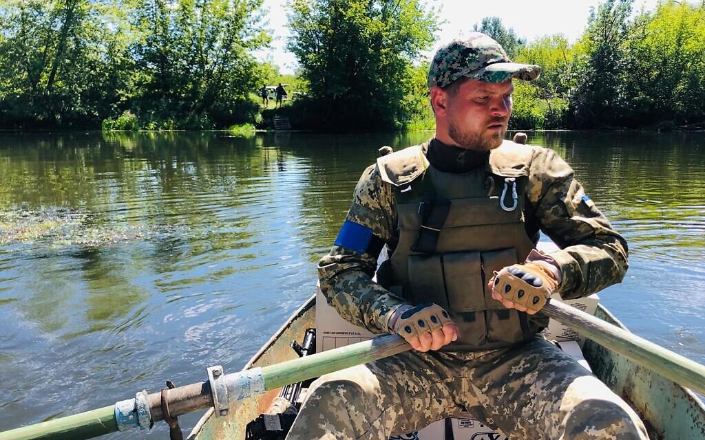 A Ukrainian soldier ferries supplies across the Siverskyi Donets River near Zadonets'ke, July 29, 2022 (Lazar Berman/The Times of Israel)