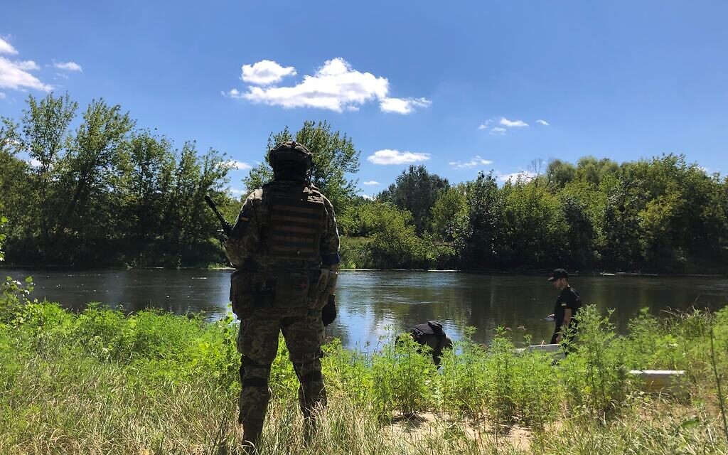 A Ukrainian soldier observes as supplies are ferried across the Siverskyi Donets River near Zadonets'ke, July 29, 2022 (Lazar Berman/The Times of Israel)