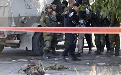 Israeli soldiers and police officers are seen at the scene of a stabbing attack near the West Bank city of Hebron, September 2, 2022 (HAZEM BADER / AFP)
