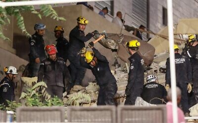 Jordanian rescue workers search for missing persons under the rubble of a four-story residential building that collapsed in central Amman, on September 13, 2022. (Khalil MAZRAAWI / AFP)