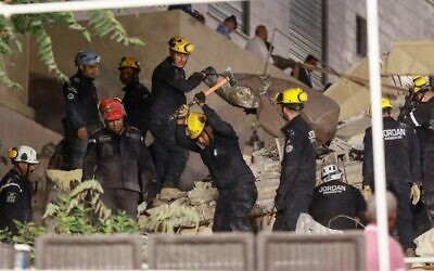 Jordanian rescue workers search for missing persons under the rubble of a four-storey residential building which collapsed in central Amman, on September 13, 2022. (Khalil MAZRAAWI/AFP)