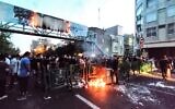 A picture obtained by AFP outside Iran on September 21, 2022, shows Iranian demonstrators burning a rubbish bin in the capital Tehran during a protest for Mahsa Amini, days after she died in police custody. (AFP)