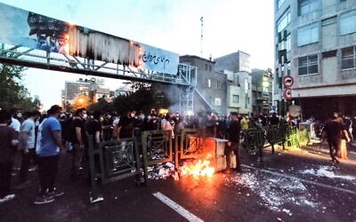 A picture obtained by AFP outside Iran on September 21, 2022, shows Iranian demonstrators burning a rubbish bin in the capital Tehran during a protest for Mahsa Amini, days after she died in police custody. (AFP)