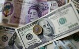 This file photo taken on April 22, 2022 shows pounds and US dollar banknotes displayed on a table in London. (Tolga Akmen/AFP)