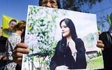 A woman holds up a sign depicting a picture of 22-year-old Mahsa Amini, an Iranian woman who died while in the custody of Iranian authorities, during a solidarity demonstration in Syria's northeastern city of Hasakeh on September 25, 2022. (Delil SOULEIMAN / AFP)