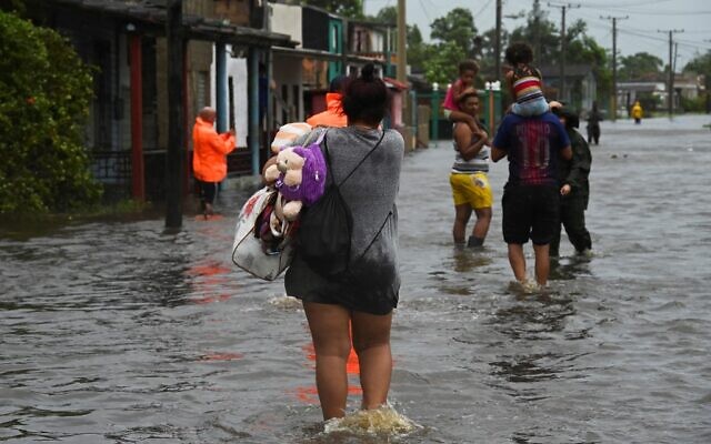 People walk through a flooded street in Batabano, Cuba, during the passage of hurricane Ian, on September 27, 2022. (YAMIL LAGE / AFP)