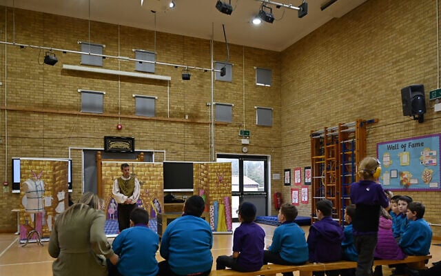 A teacher soothes a student during a theater show at the Gesher School in London, March 7, 2022. (Cnaan Liphshiz/ JTA)