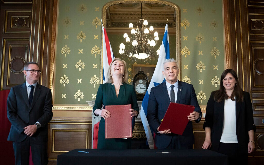 Foreign Secretary Liz Truss, center left, and Israeli Foreign Minister, Yair Lapid, center right, sign a memorandum of understanding at the Commonwealth And Development Office in London watched by the British Ambassador to Israel, Neil Wigan, left, and Israeli Ambassador to the United Kingdom, Tzipi Hotovely, right, where they held meetings and a news conference to discuss closer collaboration between the UK and Israel, in London, November 29, 2021. (Stefan Rousseau/Pool via AP)