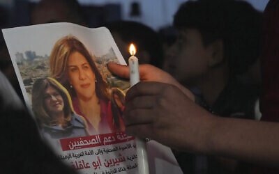 A Palestinian holds a light candle and a picture of slain Al Jazeera journalist Shireen Abu Akleh, to condemn her killing, in front of the office of Al Jazeera network, in Gaza City, May 11, 2022. (AP Photo/Adel Hana, File)