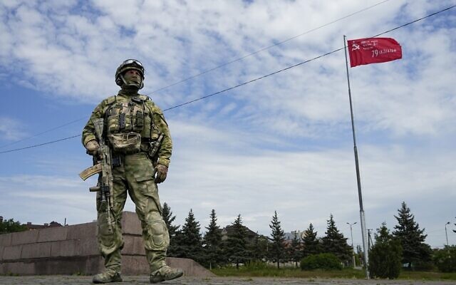 A Russian soldier guards an area near a memorial in Kherson region, south Ukraine, May 20, 2022, with a replica of the Victory banner marking the 77th anniversary of the end of World War II in the background. (AP) A Russian soldier guards an area near a memorial in Kherson region, south Ukraine, May 20, 2022, with a replica of the Victory banner marking the 77th anniversary of the end of World War II in the background. (AP)