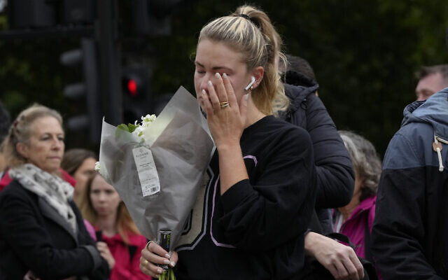 A mourner puts flowers at the gates of Buckingham Palace in London, September 9, 2022. (AP Photo/Kirsty Wigglesworth)