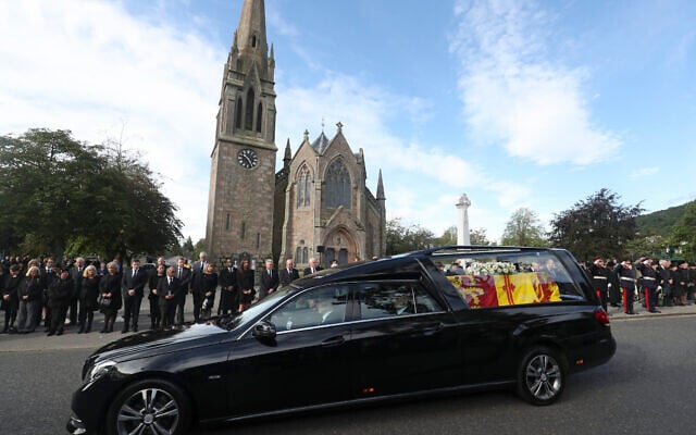 Members of the public line the streets in Ballater, Scotland, as the hearse carrying the coffin of Queen Elizabeth II passes through as it makes its journey to Edinburgh from Balmoral in Scotland, Sunday, Sept. 11, 2022. The Queen's coffin will be transported Sunday on a journey from Balmoral to the Palace of Holyroodhouse in Edinburgh, where it will lie at rest before being moved to London later in the week. (AP Photo/Scott Heppell)