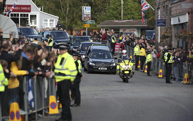 Members of the public line the streets in Ballater, Scotland, as the hearse carrying the coffin of Queen Elizabeth II passes through as it makes its journey to Edinburgh from Balmoral in Scotland, Sept. 11, 2022 (AP Photo/Scott Heppell)
