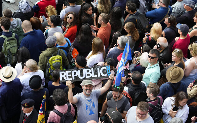 A man holds up a sign among members of the public attending a public Proclamation to announce the Accession of King Charles III, outside St Giles Cathedral, on the Royal Mile, in Edinburgh, Scotland, September 11, 2022. (Petr David Josek/AP)