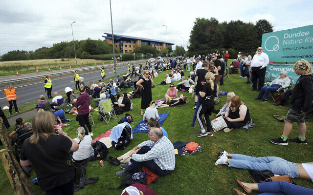 Members of the public await the hearse carrying the coffin of Queen Elizabeth II, passing through Dundee, Scotland, September 11, 2022. (Michael Boyd/PA via AP)