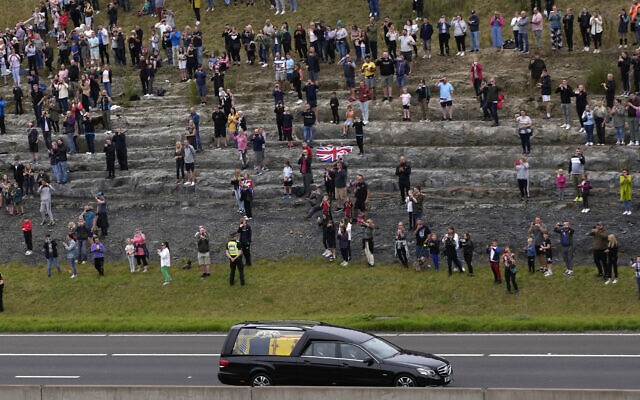 Spectators watch as the cortege with the hearse carrying the coffin of Queen Elizabeth II drives on the M90 motorway as it makes its journey to Edinburgh from Balmoral in Scotland, September 11, 2022. (Alastair Grant/AP)