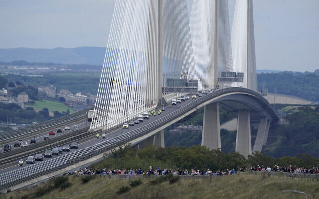 The hearse carrying the coffin of Queen Elizabeth II, draped with the Royal Standard of Scotland, passing over the Queensferry Crossing in Scotland, as it continued its journey to Edinburgh from Balmoral, September 11, 2022. (Owen Humphreys/PA via AP)