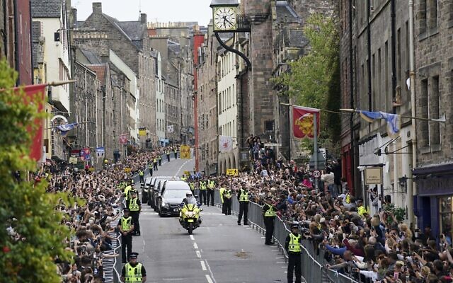 The hearse carrying the coffin of Queen Elizabeth II, draped with the Royal Standard of Scotland, passes along Canongate towards the Royal Mile as it completes its journey from Balmoral to the Palace of Holyroodhouse in Edinburgh, September 11, 2022. (Jacob King/Pool Photo via AP)