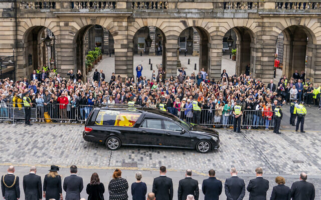 The hearse carrying the coffin of Queen Elizabeth II, draped with the Royal Standard of Scotland, passes the City Chambers on the Royal Mile, Edinburgh, on the journey from Balmoral to the Palace of Holyroodhouse in Edinburgh, September 11, 2022. (Jane Barlow/Pool Photo via AP)