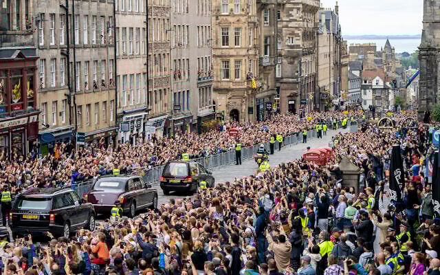 The hearse carrying the coffin of Queen Elizabeth II, draped with the Royal Standard of Scotland, passes on the Royal Mile, Edinburgh, September 11, 2022. (Jane Barlow/Pool Photo via AP)