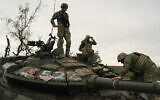 Ukrainian servicemen stand atop a destroyed Russian tank in a retaken area near the border with Russia in Kharkiv region, Ukraine, September 17, 2022. (AP Photo/Leo Correa)