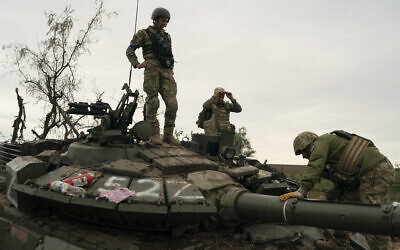 Ukrainian servicemen stand atop a destroyed Russian tank in a retaken area near the border with Russia in Kharkiv region, Ukraine, September 17, 2022. (AP Photo/Leo Correa)
