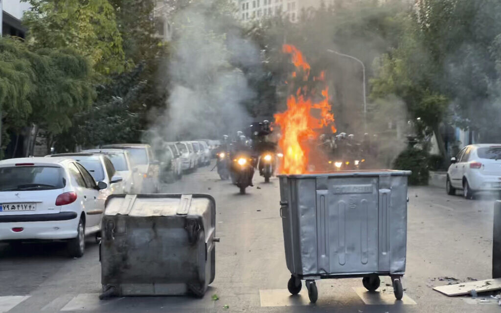 In this Sept. 20, 2022, photo taken by an individual not employed by the Associated Press and obtained by the AP outside Iran, a trash bin is burning as anti-riot police arrive during a protest over the death of a young woman who had been detained for allegedly violating the country's conservative dress code, in downtown Tehran, Iran (AP Photo) In this Sept. 20, 2022, photo taken by an individual not employed by the Associated Press and obtained by the AP outside Iran, a trash bin is burning as anti-riot police arrive during a protest over the death of a young woman who had been detained for allegedly violating the country's conservative dress code, in downtown Tehran, Iran (AP Photo)