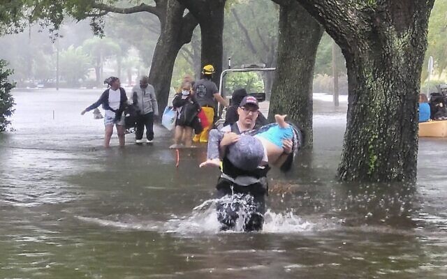 In this photo provided by the Orange County Fire Rescue's Public Information Office, firefighters in Orange County, Florida., help people stranded by Hurricane Ian, September 29, 2022. (Orange County Fire Rescue's Public Information Office via AP)