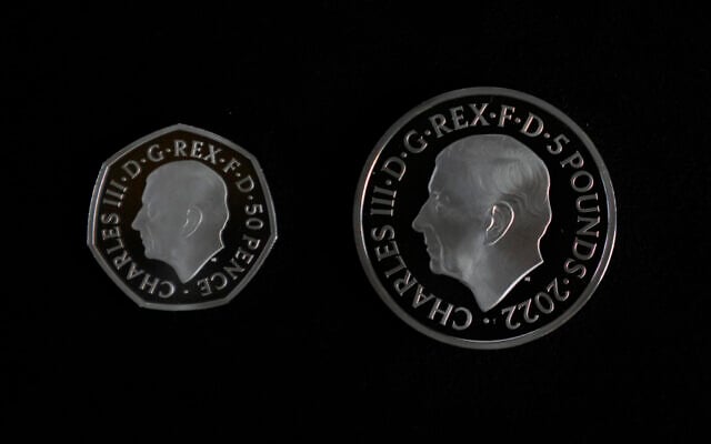 Two new coins bearing official coinage portrait of King Charles III, on the left is the new 50 pence coin, and right is the new 5 pound commemorative coin, which will be among the first coins to bear the new king's head, during a press preview in London, September 29, 2022. (AP Photo/Alastair Grant)
