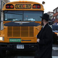 Illustrative: A man walks by school bus with Yiddish signage in Borough Park, Brooklyn, New York City, January 1, 2014. (Nati Shohat/Flash90)