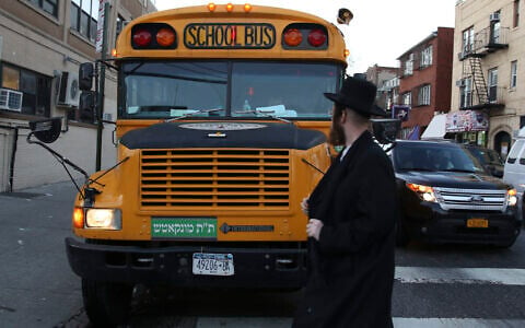 Illustrative: A man walks by school bus with Yiddish signage in Borough Park, Brooklyn, New York City, January 1, 2014. (Nati Shohat/Flash90)