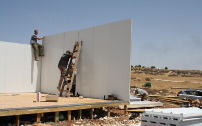 Settler activists rebuild one of the structures at the settlement outpost of Ramat Migron on August 16, 2022. (Jeremy Sharon/Times of Israel)