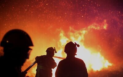 Firefighters spray water as they try to douse a fire near the village of Biguglia, Corsica island, France, as some hundreds of firefighters battle blazes fanned by high winds in more than a dozen zones in the Riviera region of southern France, on July 25, 2017. (AP Photo/Raphael Poletti, FILE)
