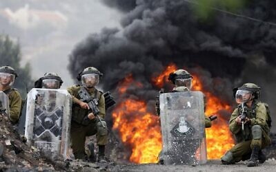 Palestinian demonstrators take cover during clashes with Israeli soldiers following a protest against the expropriation of Palestinian land by Israel in the village of Kfar Qaddum in the West Bank on October 7, 2022. (JAAFAR ASHTIYEH / AFP)